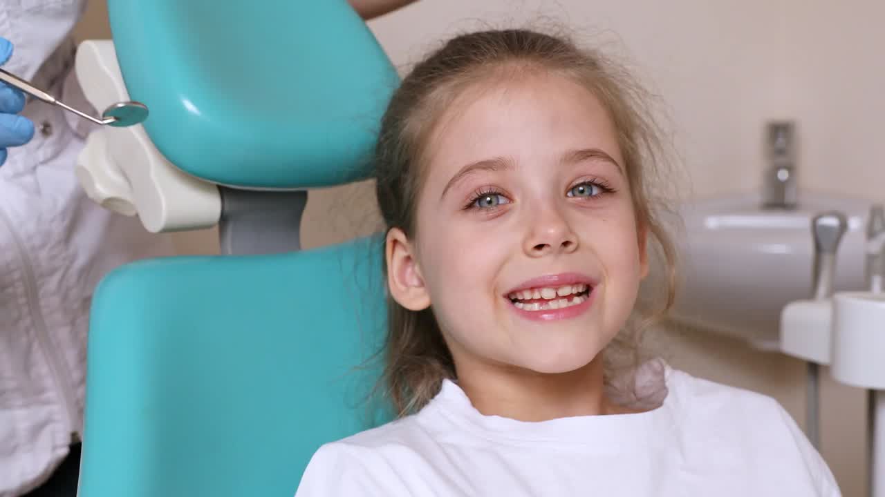 Happy young girl smiling in a teal dental chair
